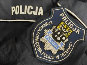 Naszywka Komendy Powiatowej Policji w Trzebnicy na kurtce służbowej. Obok znajduje się napis Policja.