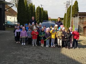 Dzieci ze Szkoły Podstawowej w Barkowie stoją przed oznakowanym radiowozie policyjnym wraz z policjantami. Zdjęcie wykonano na parkingu służbowym komisariatu.
