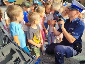 Policjant ruchu drogowego pokazuje dzieciom urządzenie do pomiaru prędkości