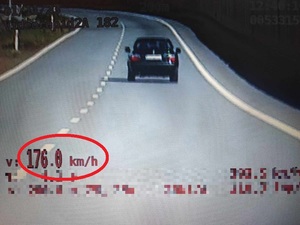 Samochód osobowy jadący prawym padem jezdni. W prawym dolnym rogu znajduje się prędkość 176 kilometrów na godzinę. Prędkość tak jest zaznaczona w czerwonym kółku.