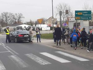 Policjanci zabezpieczają ulicę aby dzieci idące na pierwszy dzień wiosny mogły dojść bezpiecznie