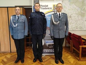 Zdjęcie przedstawia Komendanta Powiatowego Policji w Trzebnicy w towarzystwie Naczelnika Wydziału Prewencji oraz nowo przyjętego funkcjonariusza