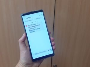 Zdjęcie przedstawia telefon komórkowy trzymany w ręce z otrzymaną wiadomością dotyczącą zaległości w opłacie