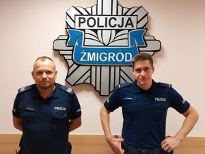 Na zdjęciu znajduje się dwóch policjantów w mundurach granatowych na tle gwiazdy z napisem KP Żmigród