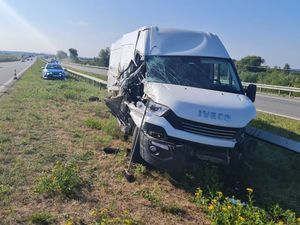 Samochód marki Iveco z widoczny uszkodzeniem prawego przodu w tle radiowóz policyjny