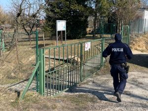 Policjant idzie na kontrolę ogródków działkowych