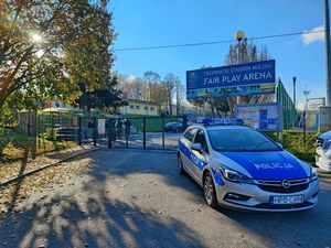 Oznakowany radiowóz policyjny przed bramą wjazdową na stadion