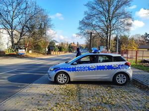 Oznakowany radiowóz policyjny stoi przy drodze dojazdowej na stadion