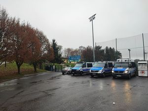 Policyjne oznakowane radiowozy typu bus stoją przed stadionem w celu zabezpieczenia meczu