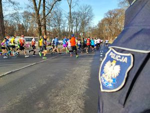 Osoby biegnące oraz plakietka policji