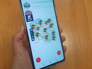 Telefon komórkowy trzymany w ręce a na wyświetlaczu mapa Polski z otwartą aplikacją Krajowej Mapy Zagrożeń Bezpieczeństwa.