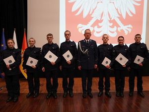 Nowoprzyjęci policjanci trzymając akty ślubowania stoją w towarzystwie Komendanta Powiatowego Policji w Trzebnicy komisarza Grzegorza Maciąga