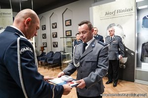 Funkcjonariusz odbiera z rąk Zastępcy Komendanta Wojewódzkiego Policji we Wrocławiu list gratulacyjny oraz książkę