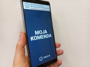 Telefon typu smartfon trzymany w ręce, na wyświetlaczu znajduje się otwarta aplikacja Moja Komenda