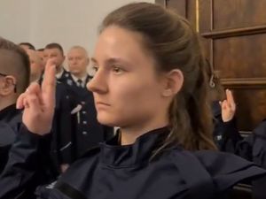 Policjantka podczas uroczystego ślubowania, ma uniesioną dłoń w trakcie wymawiania roty ślubowania