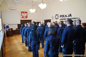 Wszyscy wyróżnieni stoją tyłem do zdjęcia. Przemawia Komendant Wojewódzki Policji we Wrocławiu