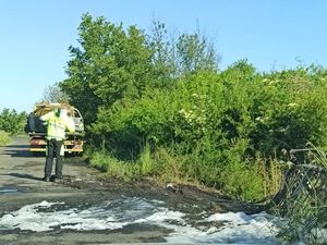 Na odcinku drogi widoczne ślady spalenia oraz piany gaśniczej. W tle widać lawetę, na której umieszczony jest spalony samochód.