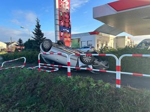samochód koloru jasnego leży na dachu przy stacji benzynowej