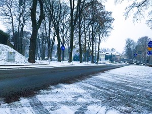 Droga w centrum Trzebnicy na której znajduje się pośniegowe błoto. Wszędzie leży śnieg.