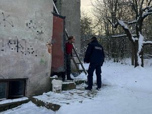 Dzielnicowy rozmawia z osobą będącą w kryzysie bezdomności. Na dworze panuje pora zimowa, na ziemi leży śnieg.