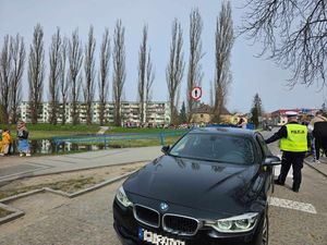 Policjanci zabezpieczają ulicę aby dzieci bezpiecznie mogły przejść nad rzekę aby topić Marzannę