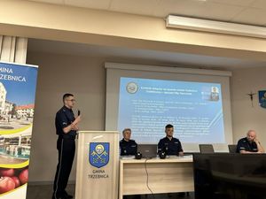 Policjant omawia ewaluację debaty, na ścianie wyświetlana jest prezentacja multimedialna, a przy stole siedzi 3 policjantów