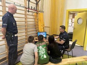 Zawodnicy wykonują testy na komputerze z przepisów ruchu drogowego, policjanci przyglądają się