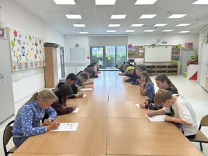 Dzieci siedząc przy stole wypełniają testy teoretyczne