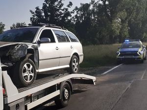 Uszkodzony pojazd znajduje się na lawecie, w tle widoczny oznakowany radiowóz policyjny