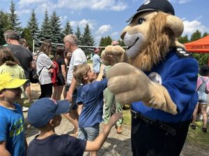 Na odbywającym się festynie dzieci przybijają tak zwaną piątkę z maskotką dolnośląskiej Policji Komisarzem Lwem