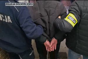 prowadzony przez policjant zatrzymany mężczyzna w kajdankach