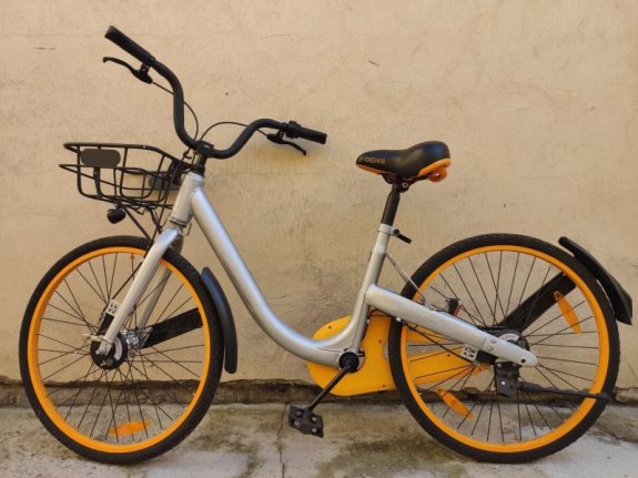 Na zdjęciu znajduje się rower typu damskiego, rama roweru jest koloru szarego, siodełko charakterystyczne koloru czarno żółte z widocznym napisem Bike, przy kierownicy znajduje się metalowy koloru czarnego koszyk.
