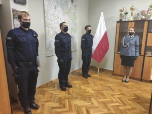 Na zdjęciu znajdują się nowo przyjęci policjanci, którzy ubrani są w mundury koloru granatowego, jest to mundur służbowy, ćwiczebny. Funkcjonariusze stoją w odległości od siebie. N zdjęciu znajduje się również I Zastępca Komendanta Powiatowego Policji w Trzebnicy młodszy inspektor Katarzyna Winter.